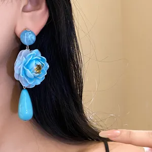 Vista dettagliata di eleganti orecchini a fiore in resina blu con pendente a goccia.