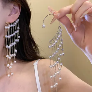 Detail of elegant pearl tassel ear cuff with long fringe design worn and hand-held