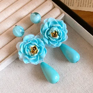 Dettaglio orecchini a forma di fiore in resina blu con pendenti a goccia e argento