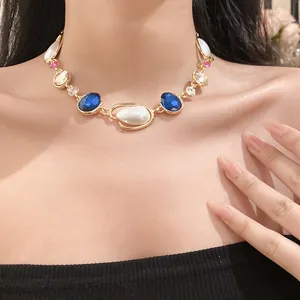 Dettaglio di una collana vintage dorata con cristalli blu e perle indossata da modella