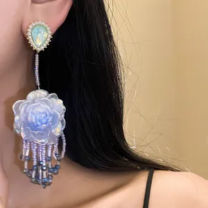 Dettaglio orecchini pendenti a fiore in resina azzurra con eleganti nappe di perline