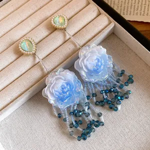 Dettaglio orecchini a rosa in resina azzurra con nappe di perline scintillanti