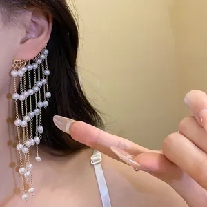 Detailed view of an elegant gold-tone pearl tassel ear cuff worn on a model's ear