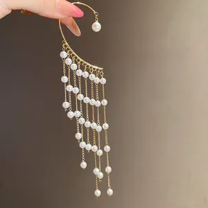 Detailed close-up showing the elegant long pearl tassel strands on a golden ear cuff
