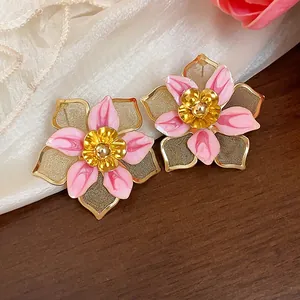 Detailed macro view of retro pink oil-dripped flower earrings with golden mesh petals