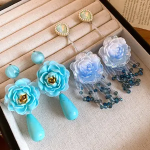 Dettaglio degli orecchini a fiore in resina blu con perni in argento su vassoio portagioie