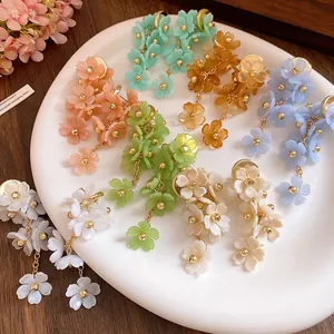 Close-up view of multiple colorful acrylic flower tassel earrings on white plate