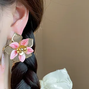 Close-up of a vintage pink enamel flower earring with gold mesh detail on a model.