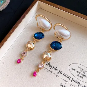 Dettaglio di orecchini vintage con perle e cristalli colorati ovali.