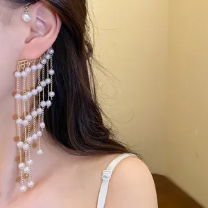 Detailed view of an elegant pearl tassel ear cuff with multi-layer gold chains on a model