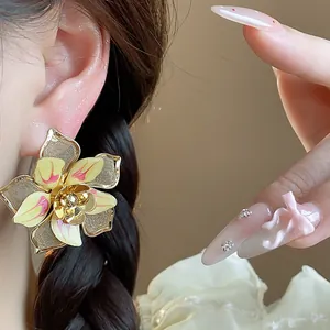 Detailed close-up of vintage gold-toned flower earring with yellow enamel petals