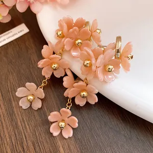 Close-up of pink acrylic flower tassel earrings with golden beads and steel needles