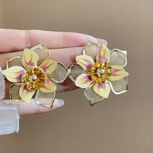 Detailed macro view of retro gold-toned flower stud earrings with yellow enamel petals