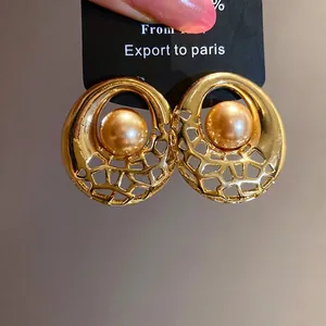 Élégantes boucles d'oreilles rondes dorées avec une grande perle de champagne au centre