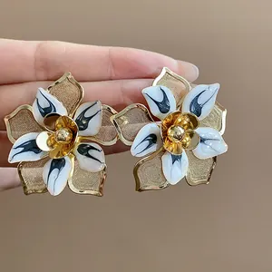 Detailed macro shot of exaggerated vintage flower stud earrings with black and white enamel