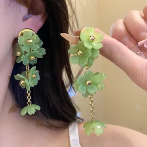 Close-up of light green acrylic flower dangle earrings with elegant gold-tone metal links.