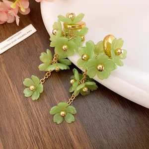 Detailed macro view of green acrylic flower tassel earrings with golden bead centers