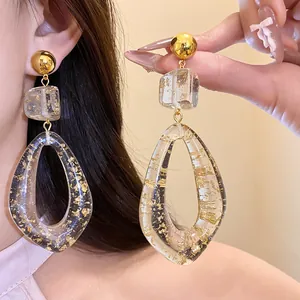 Detailed close-up of elegant clear resin drop earrings with embedded gold leaf details