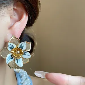 Exquisite close-up of a vintage enamel flower earring with gold mesh petals worn on an ear
