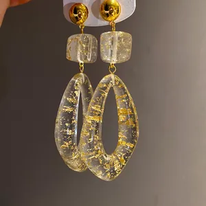 Macro view of waterdrop resin earrings with gold foil flakes and gold studs.