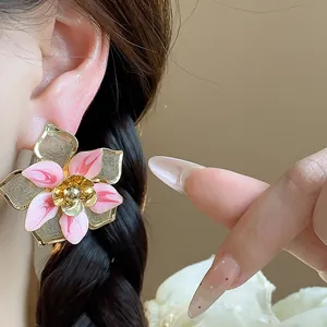Detailed view of exquisite pink enamel flower stud earrings with gold plating on ear