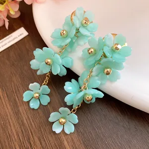 Detailed close-up showing the mint green acrylic flower petals and gold chain dangle earrings.