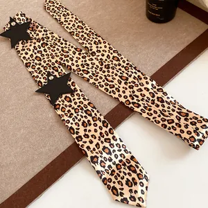 Detailed view of leopard print ribbon scarf featuring black star patches and soft silk texture