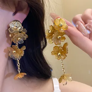 Close-up of amber acrylic flower tassel earrings showing the elegant hanging floral design.