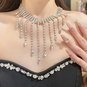Detailed view of a silver rhinestone tassel necklace with teardrop pendants on a model