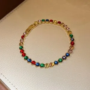 Macro view of a gold-plated bracelet with vibrant multi-colored round zircons.