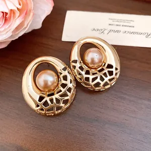Gros plan détaillé de boucles d'oreilles géométriques dorées avec une perle ronde