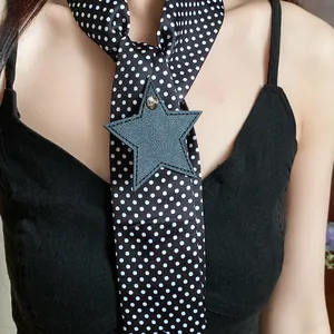 Close-up of a black and white polka dot neck scarf with a leather star charm accessory