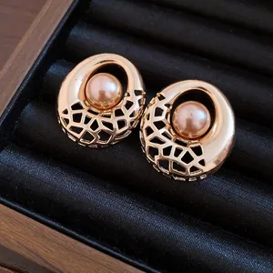 Détail de boucles d'oreilles rondes évidées avec perles sur plateau en velours