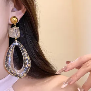 Exquisite detail of clear resin drop earrings featuring luxurious gold leaf flakes on model