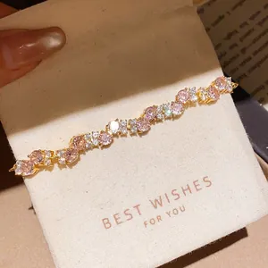 Close-up of elegant gold plated bracelet with pink zircons on a white gift pouch