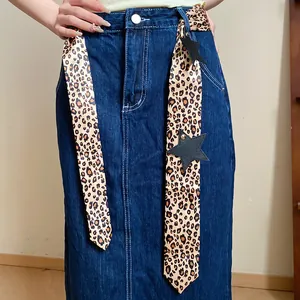Close-up detail of a leopard print skinny scarf with star charms worn on a denim skirt