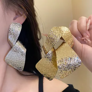 Close-up of oversized irregular crinkled texture drop earrings in gold and silver