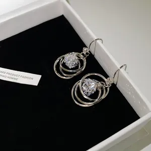 Close-up of multi-layer silver hoop earrings with central sparkling zircon detail.