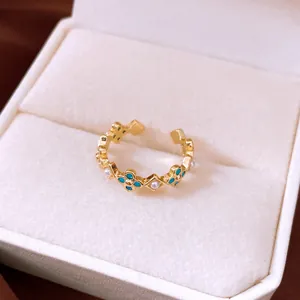Macro detail of elegant gold open ring with blue clover flowers and tiny pearls in box
