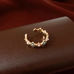 Detail view of elegant golden flower ring featuring turquoise stones and mini pearls
