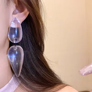 Detailed view of stylish transparent resin double teardrop earrings worn by a model