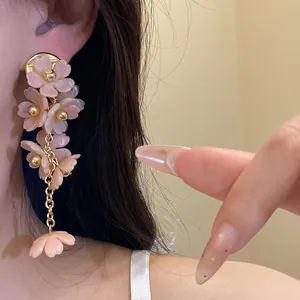 Close-up view of elegant pink acrylic flower tassel earrings worn on ear with gold studs