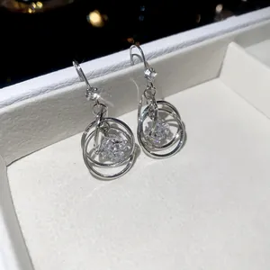 Close-up of elegant multi-layer silver-toned hoop earrings with sparkling zircon drop