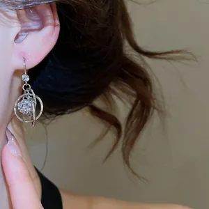 Close-up of silver orbital earrings with sparkling zirconia crystals on a female model.