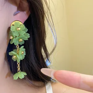 Close-up of green acrylic flower fringe earrings worn on model's ear