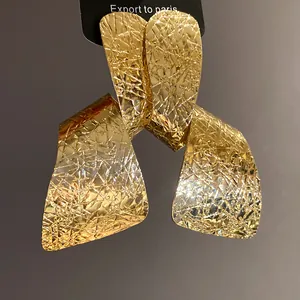 Close-up of gold irregular statement earrings with hammered texture detail.