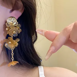Macro view of elegant amber acrylic flower tassel earrings worn on a model's ear