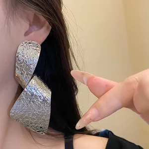 Close-up view of irregular silver textured drop earrings with exaggerated design