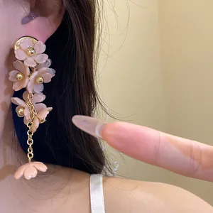 Close-up of elegant pink acrylic flower tassel earrings with gold chain on model's ear