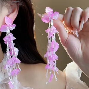Elegante, 18 Karat vergoldete Quastenohrringe mit zarten rosa Glasblüten, am Ohr präsentiert